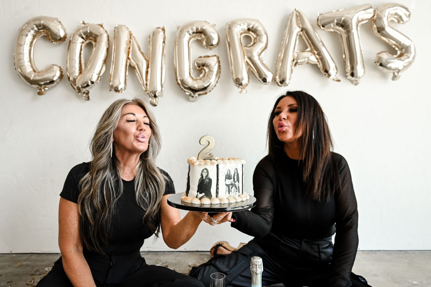 Silver balloon letters spelling CONGRATS decorate a plain white wall during a celebration.