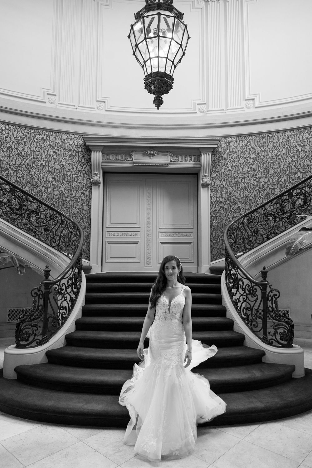 A grand black and white staircase with ornate iron railings and detailed architectural molding in an elegant setting.
