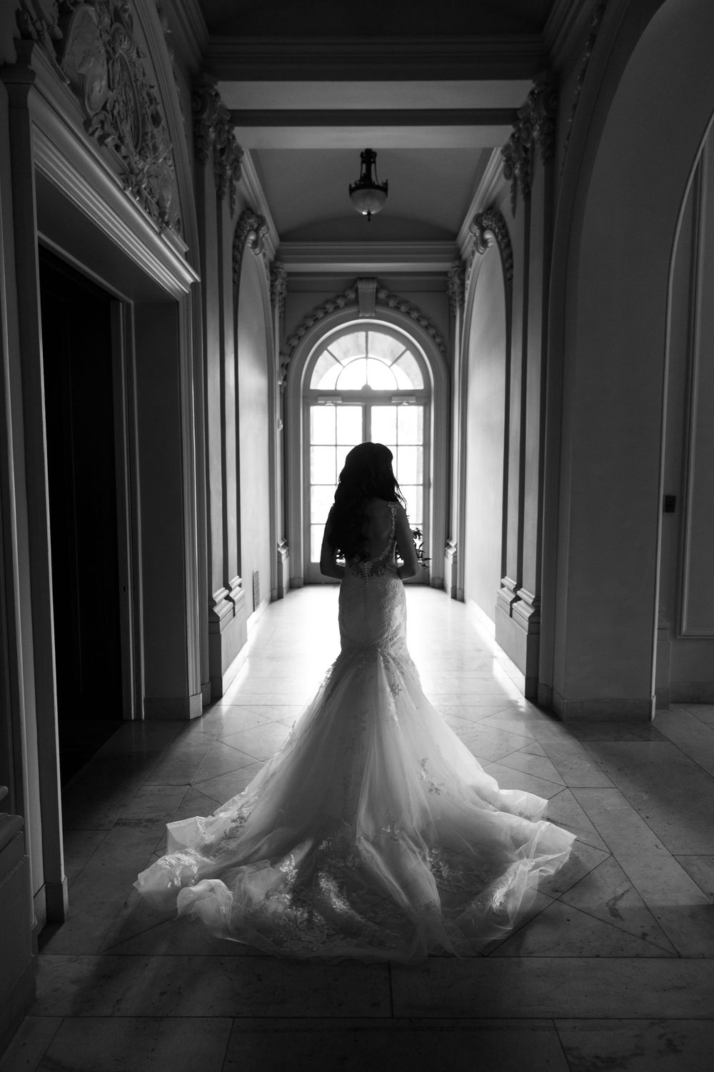 A dramatic black and white photo series shows a bride's silhouette in a flowing tulle gown walking through an elegant hallway.