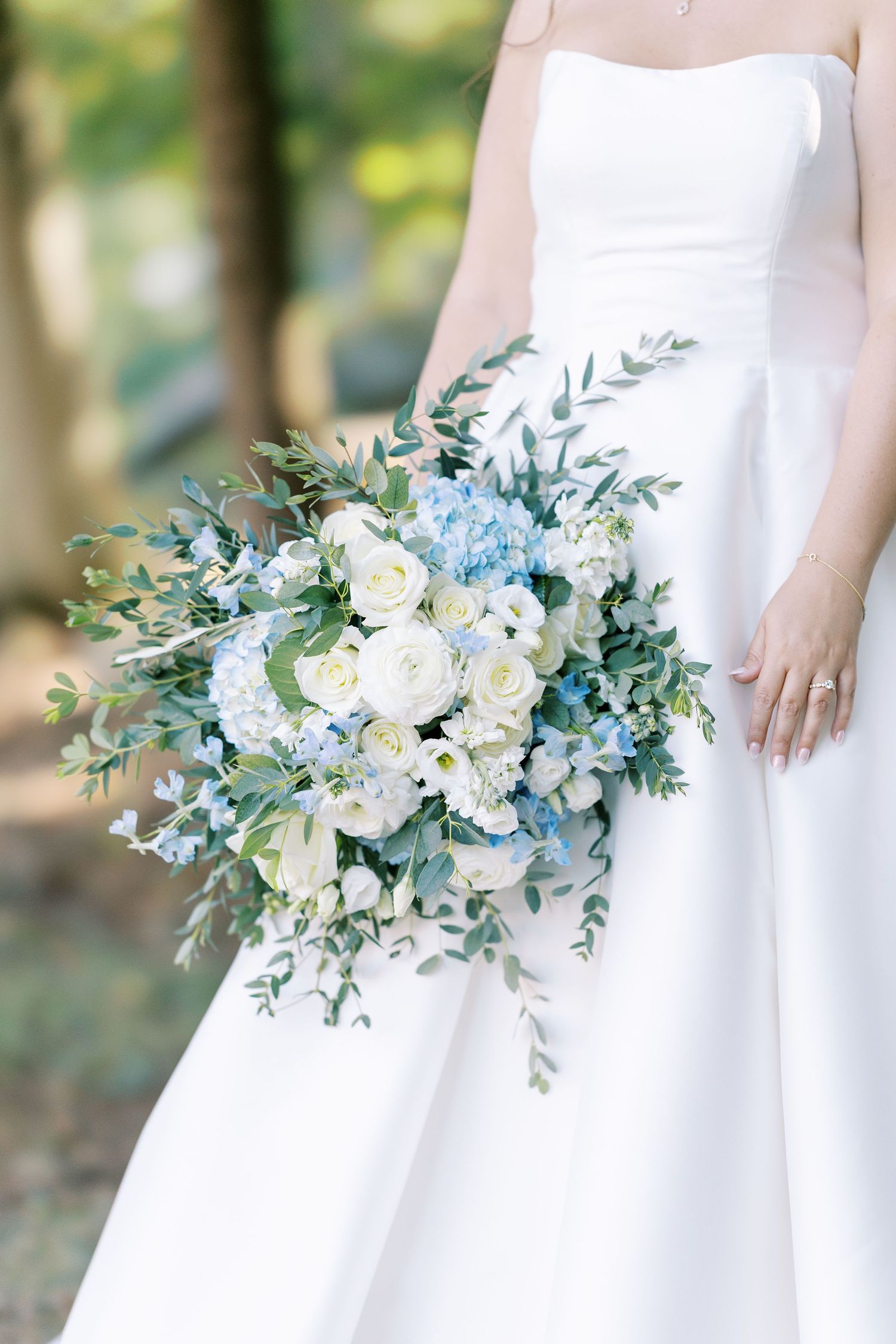 Three elegant white and blue bridal bouquets with eucalyptus and delicate flowers against a soft natural background.