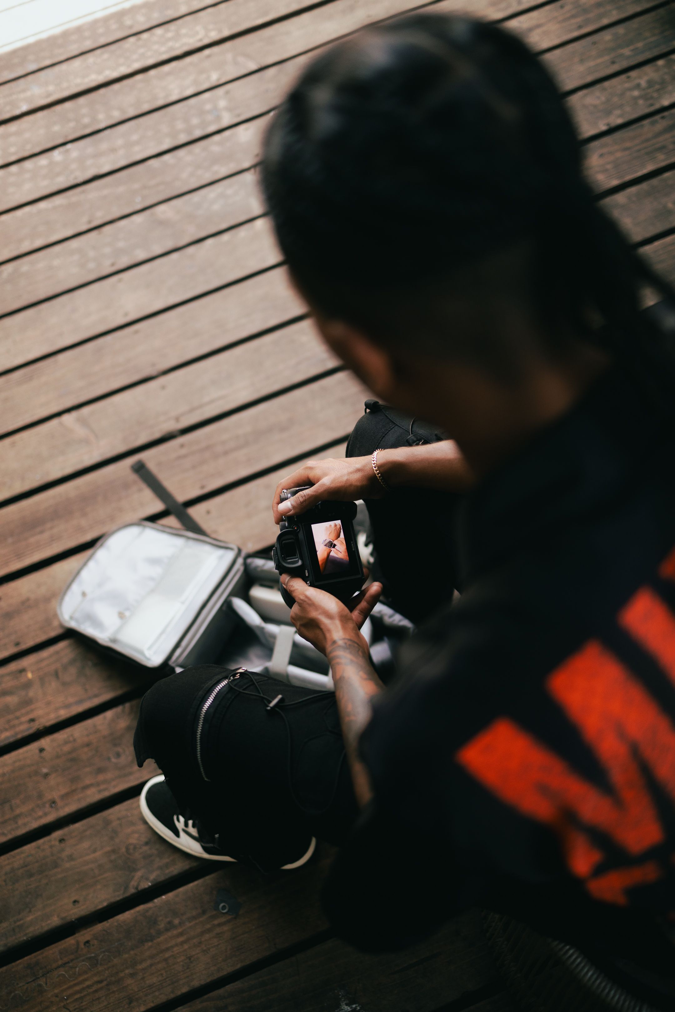 Candid urban portrait of model journaling in red MIXED EMOTIONS hoodie, Miami streetwear editorial with Pinterest lifestyle aesthetic.