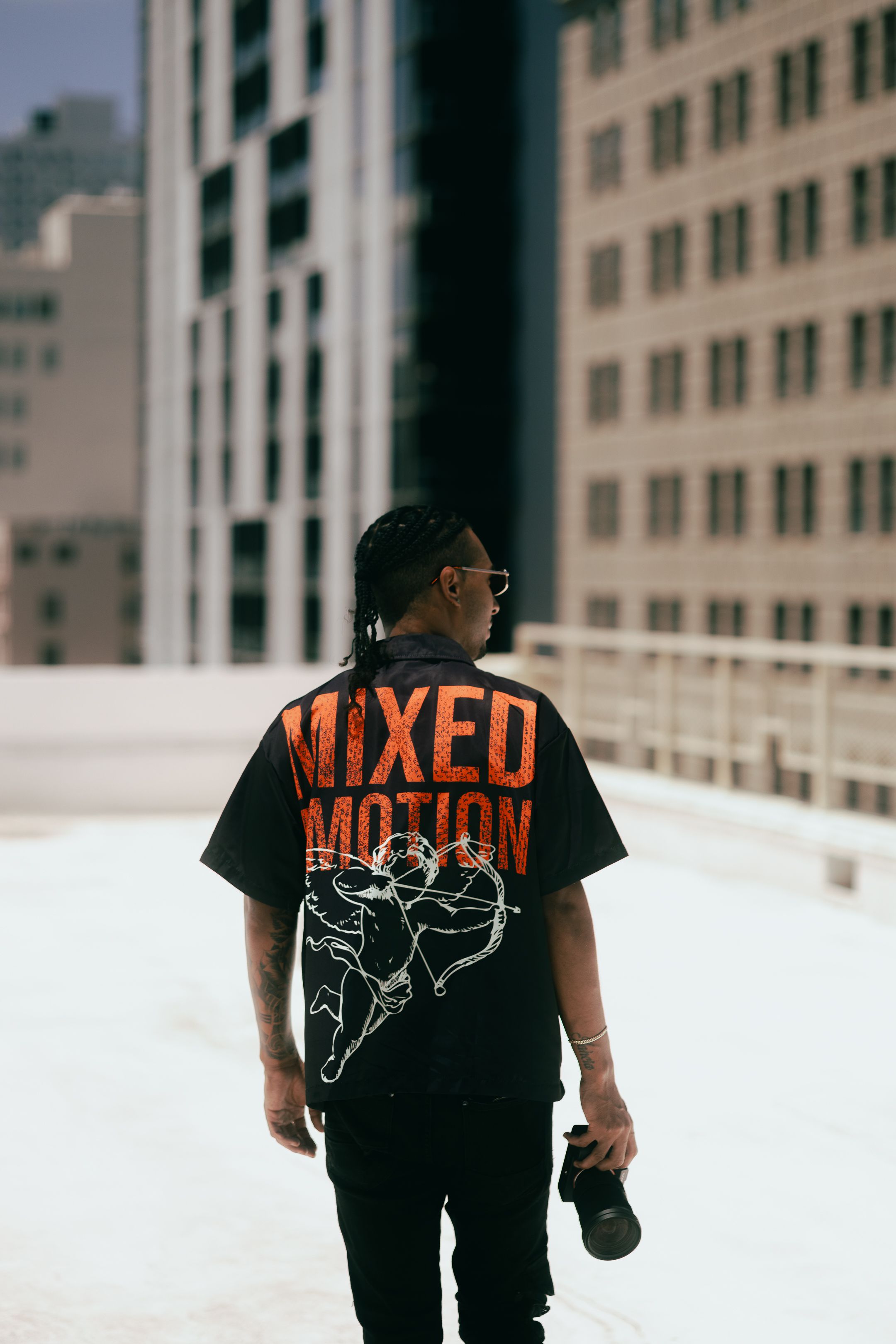 Urban fashion shoot in downtown Miami, model in MIXED EMOTIONS streetwear shirt styled with Balenciaga-inspired flair, cinematic portrait.