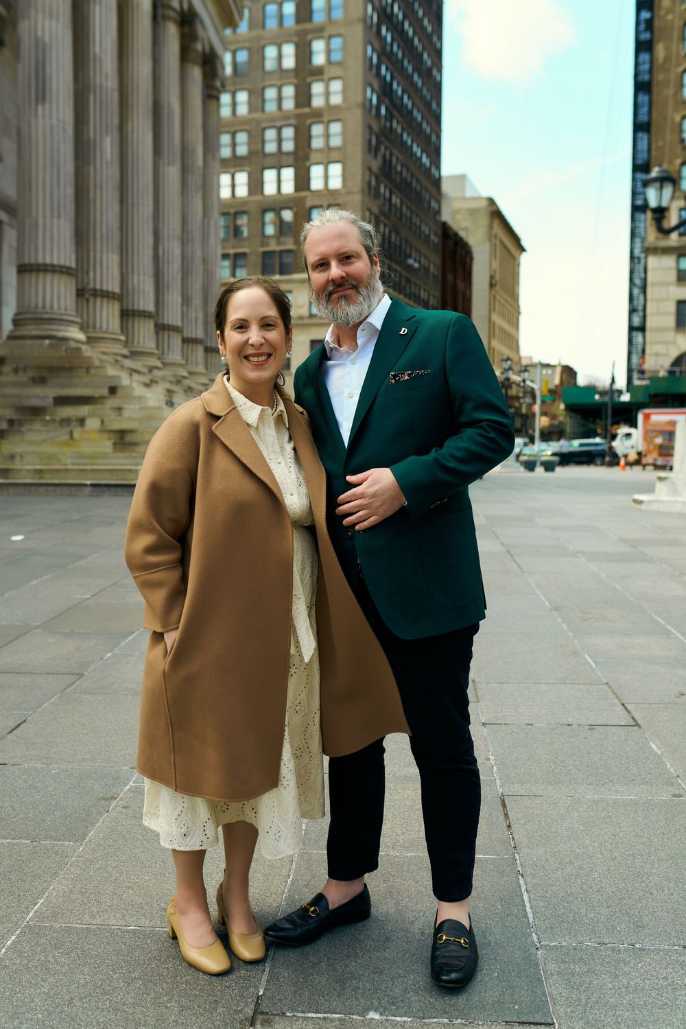 Two people stand outside a grand building with columns, showing their outfits in a series of similar poses. Wedding photography