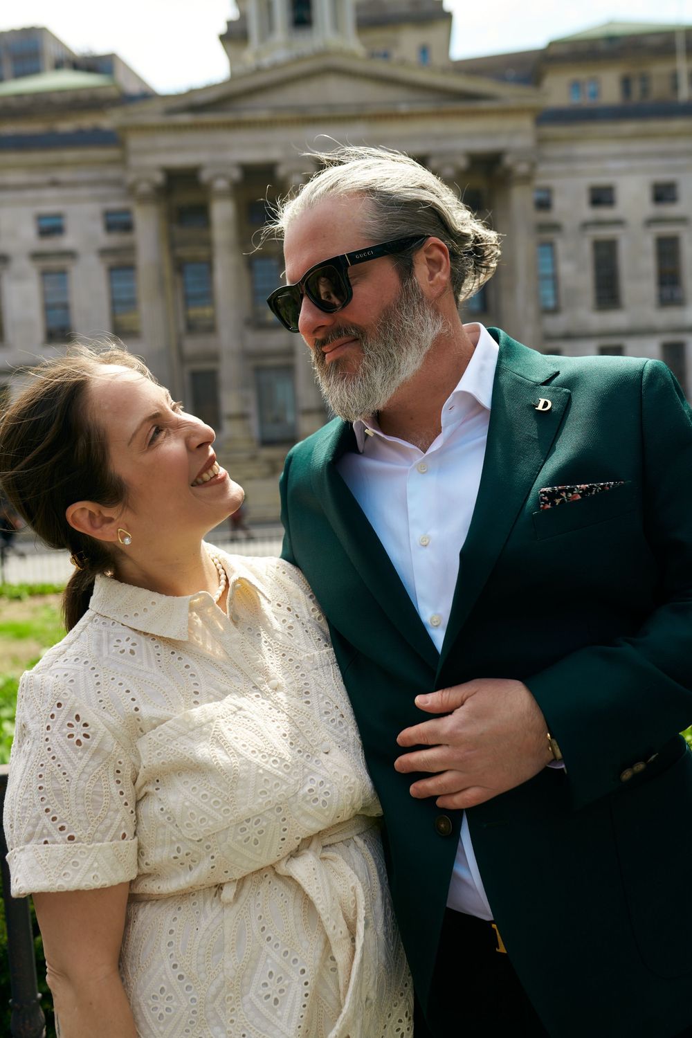 Couple in wedding attire laughs together in a series of candid outdoor photos against a classic building backdrop. wedding photography