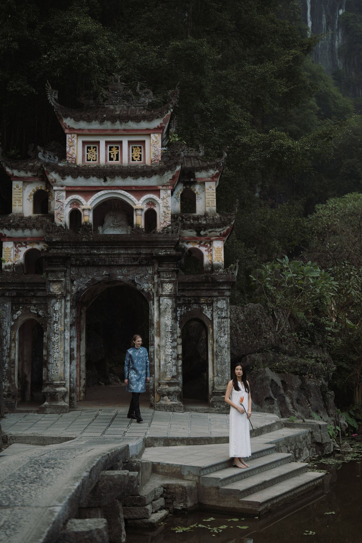 A couple poses in front of an ornate Asian temple entrance with traditional architecture.