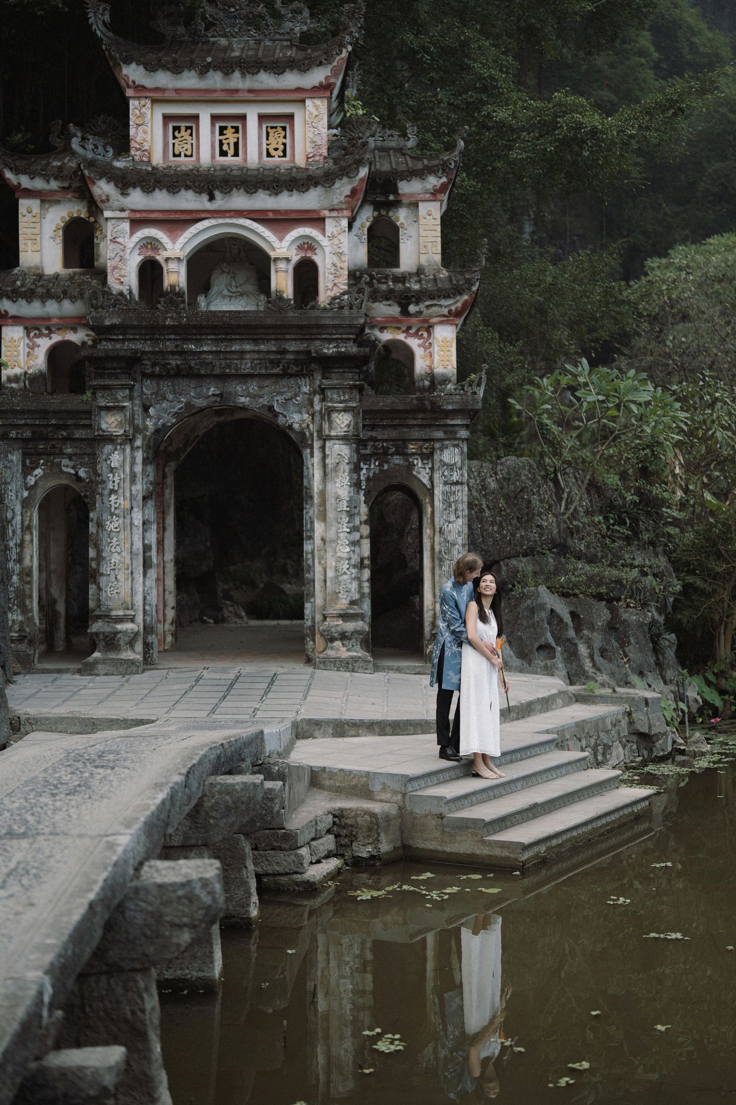 Ancient stone temple entrance with ornate archway and reflective pool in Vietnam creates atmospheric wedding photography setting.