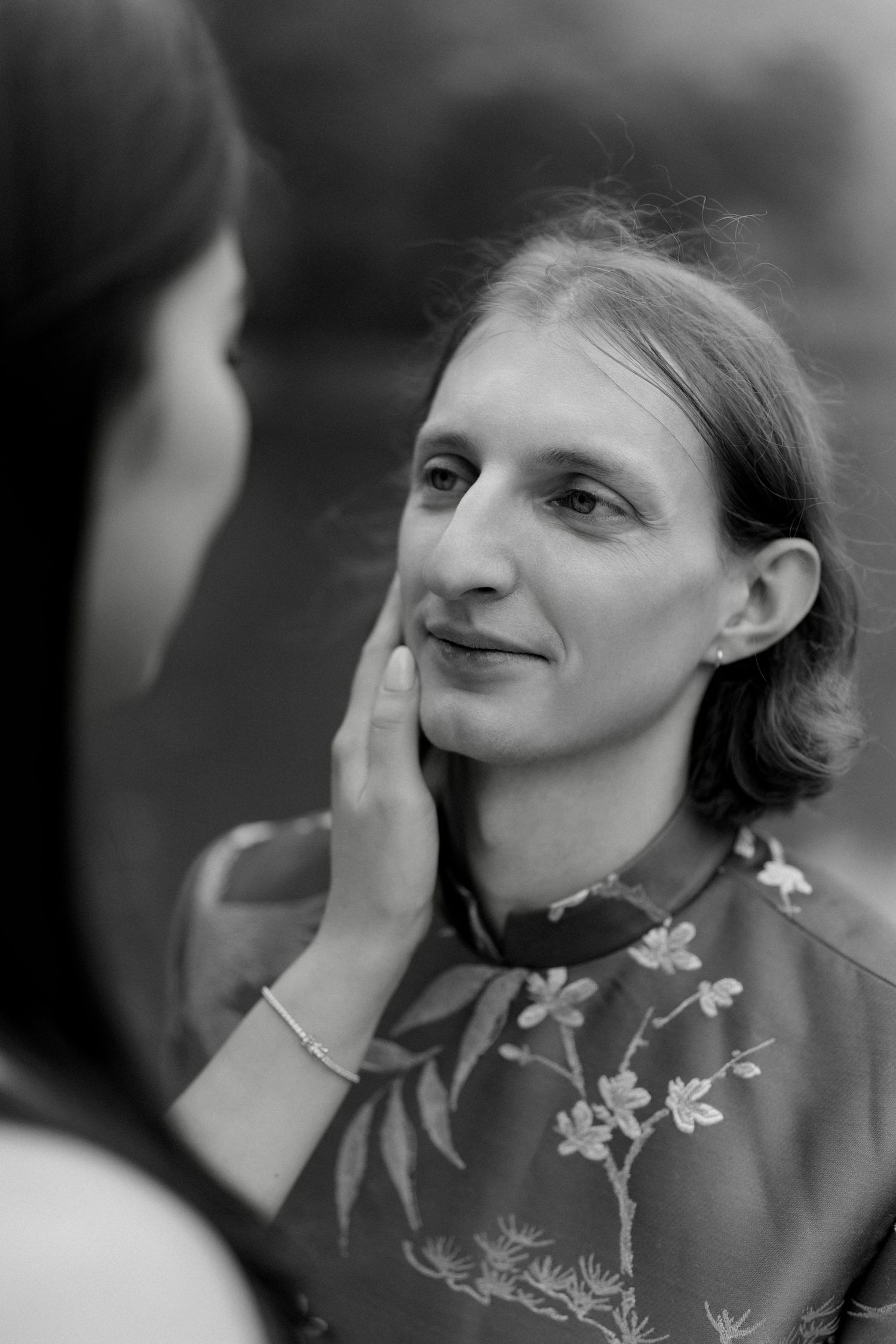 Series of black and white portraits showing person with flowers on shirt looking up and sideways with hands near face.