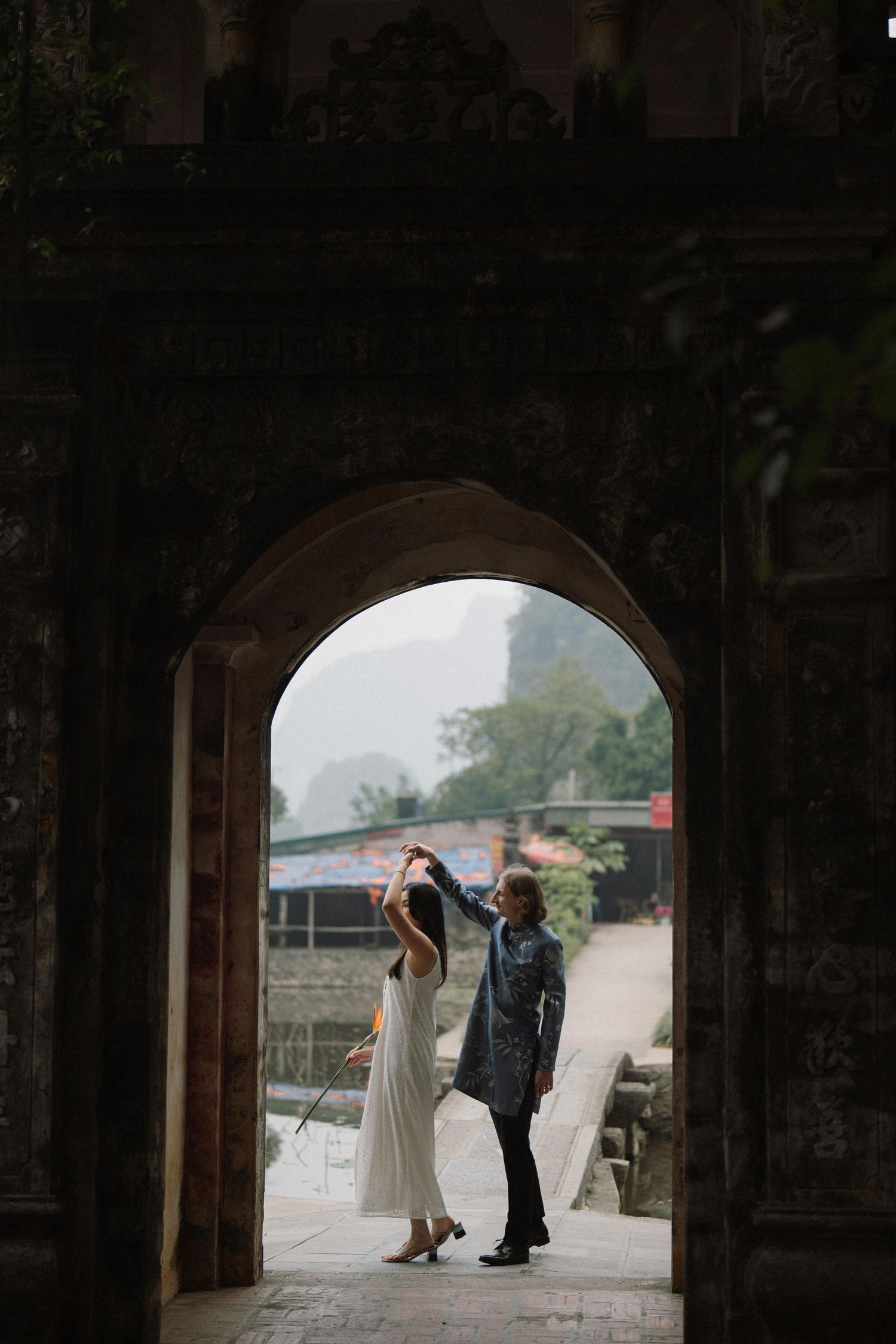 A couple shares a romantic moment under an arched temple doorway.