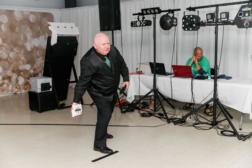 A person in black attire dances energetically on a light-colored floor with music equipment visible in the background.