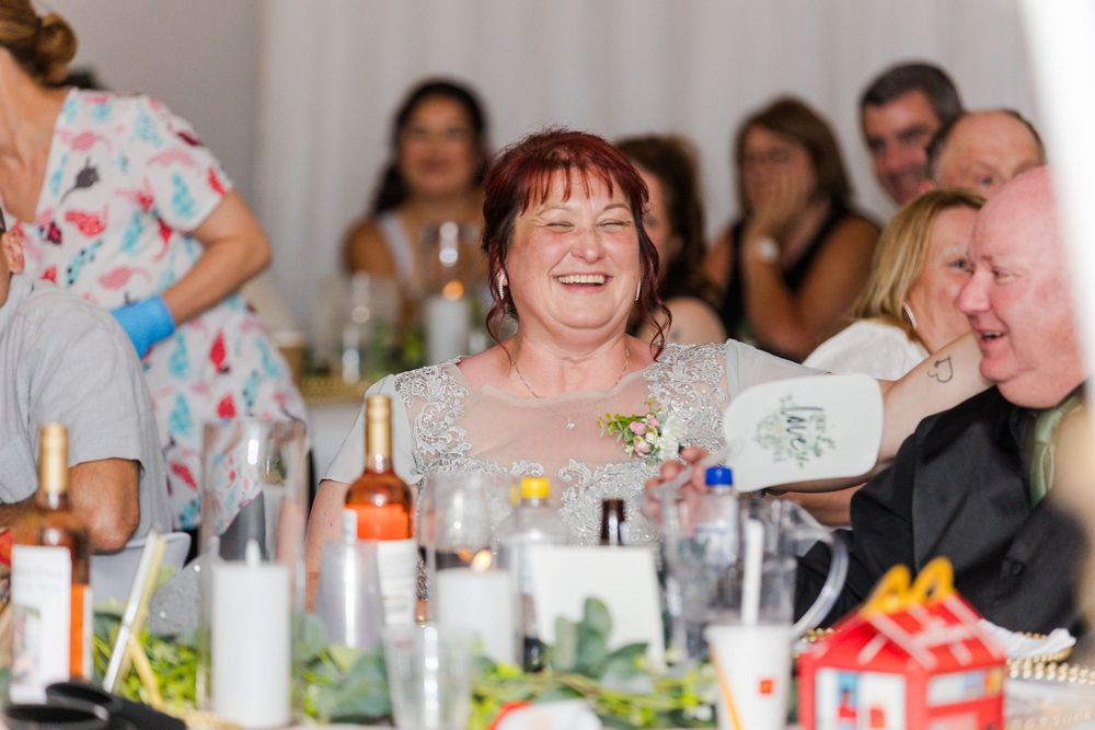Guests enjoying lively conversation and laughter during a festive dinner celebration with table settings and drinks.