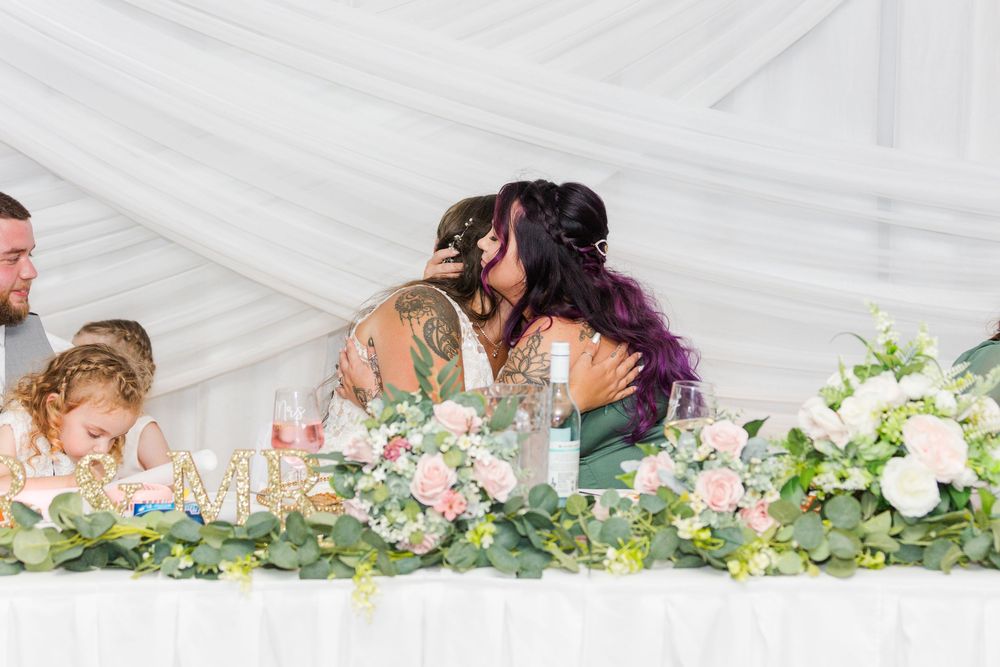 Wedding guests share an intimate moment at a reception table adorned with delicate floral arrangements.