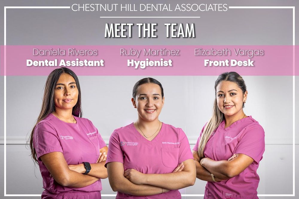 Dental office team members in pink uniforms pose for professional group photo.