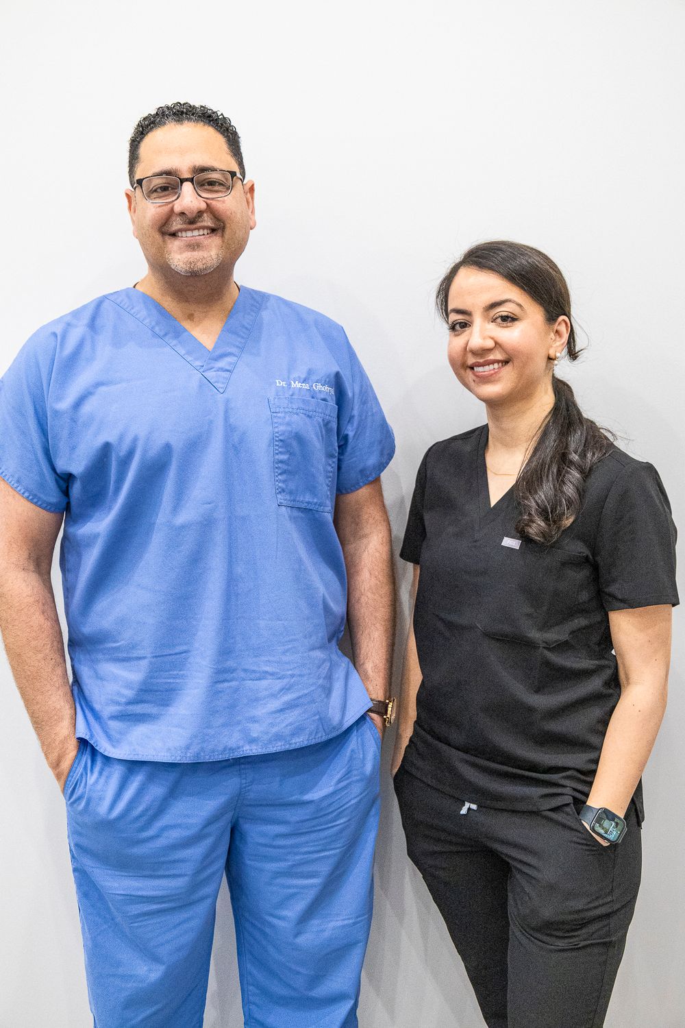 Medical team members in blue and black scrubs pose together in clinical setting.