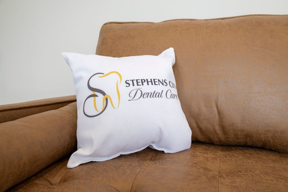 White decorative pillows with embroidered logo arranged on brown leather furniture.