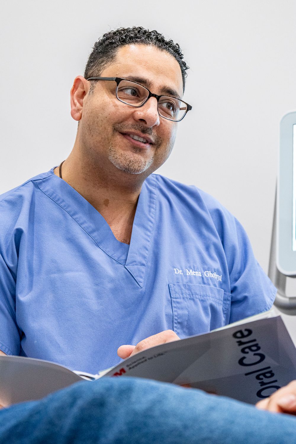 Medical professional in blue scrubs reviews patient charts with enthusiasm.
