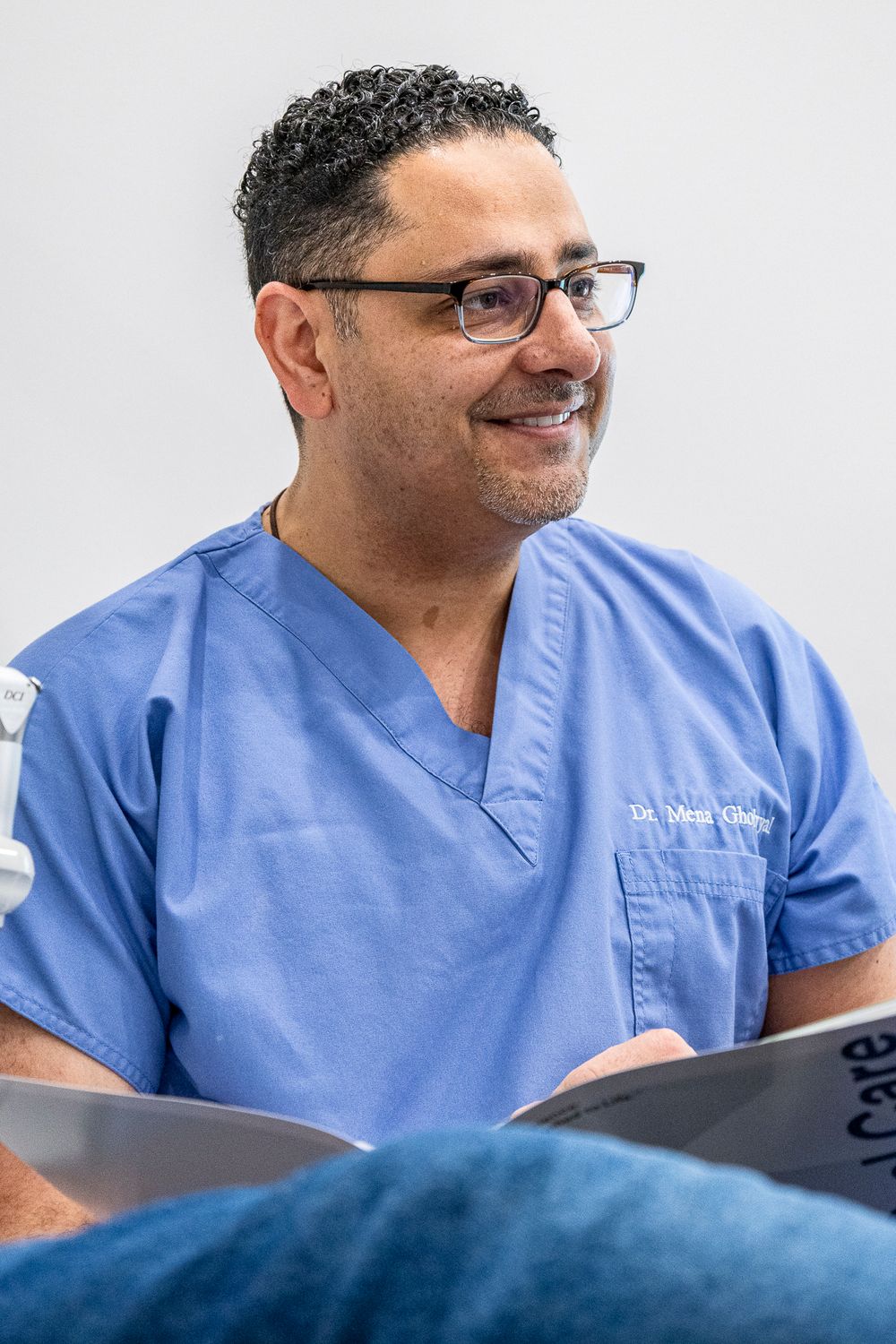 Healthcare provider in blue scrubs reviews medical documents while seated.