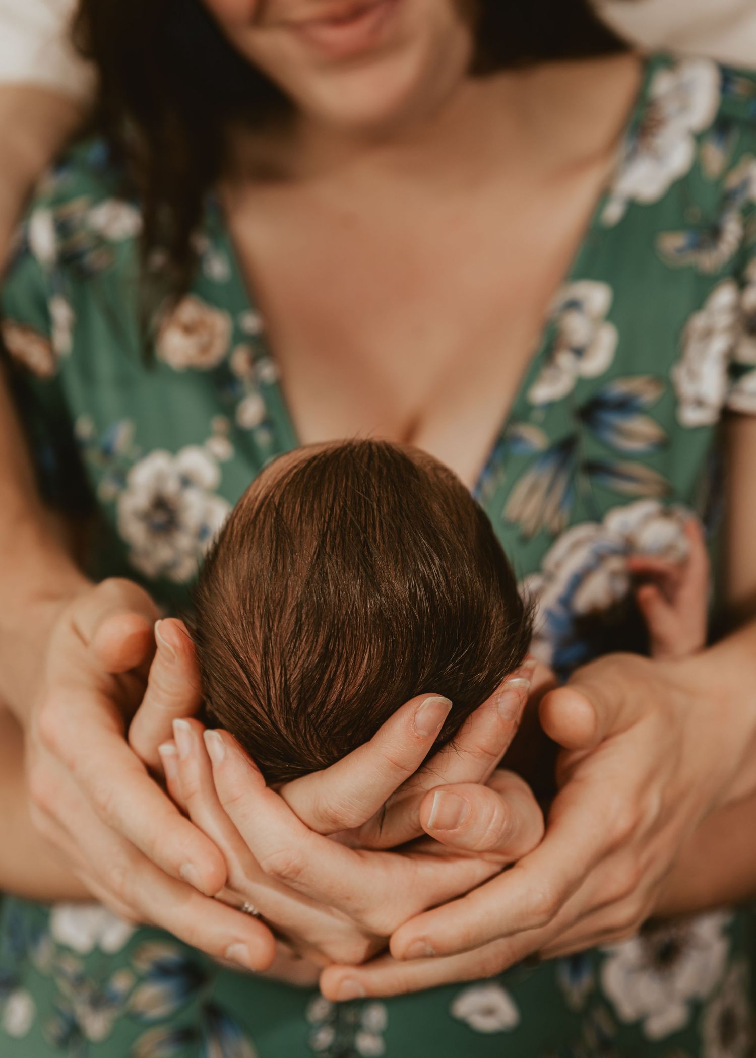 A gentle hand caresses a sleeping baby's face in an intimate close-up portrait with warm lighting.