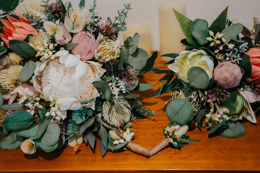 A row of romantic wedding bouquets with eucalyptus, roses and mixed flowers arranged on a wooden surface.