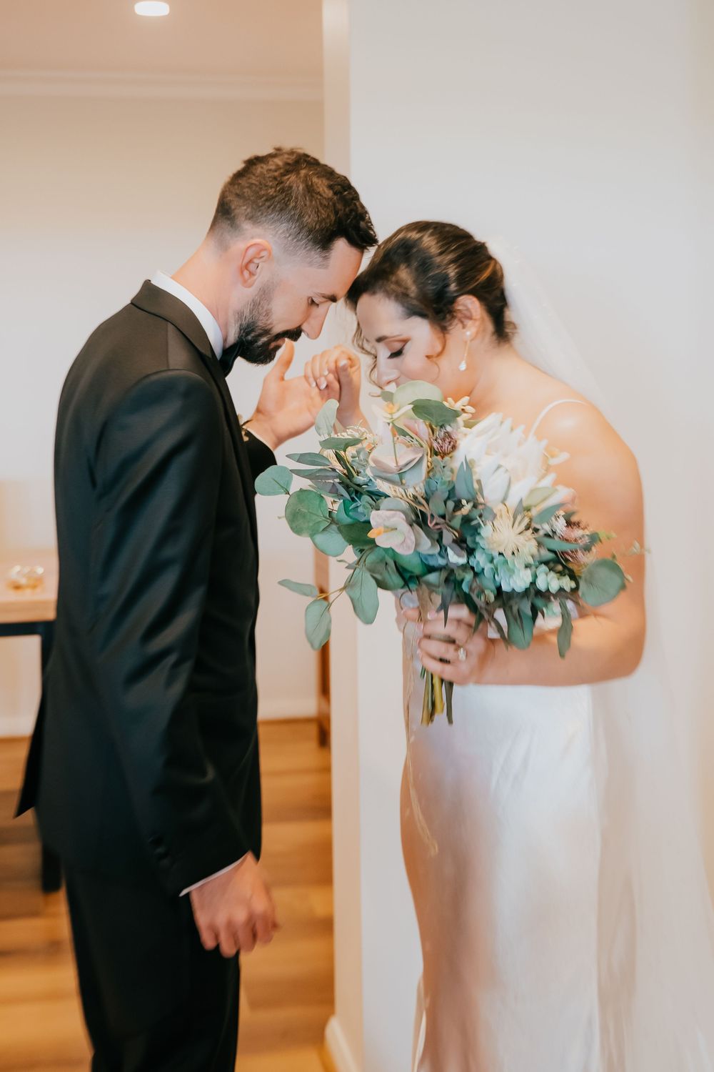 A tender first look moment between bride and groom separated by a floral arrangement at their wedding day.