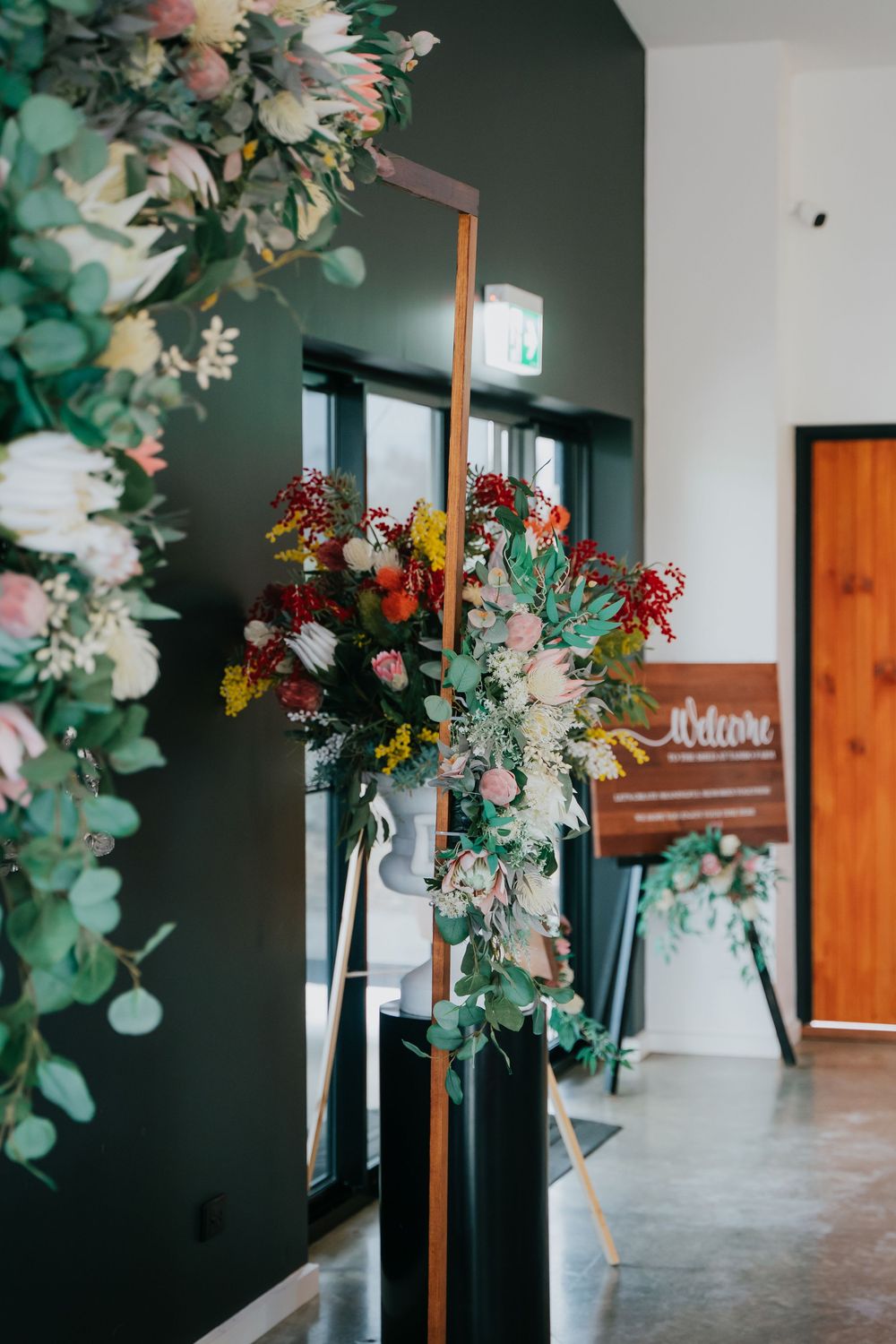 Modern hallway interior with dark green walls decorated with elegant floral arrangements and eucalyptus greenery.