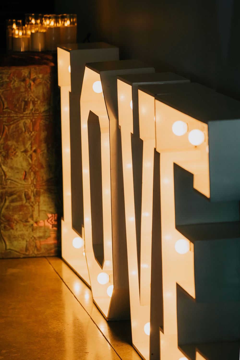 Illuminated white LOVE marquee letters create a romantic atmosphere with warm lighting on a wooden floor.