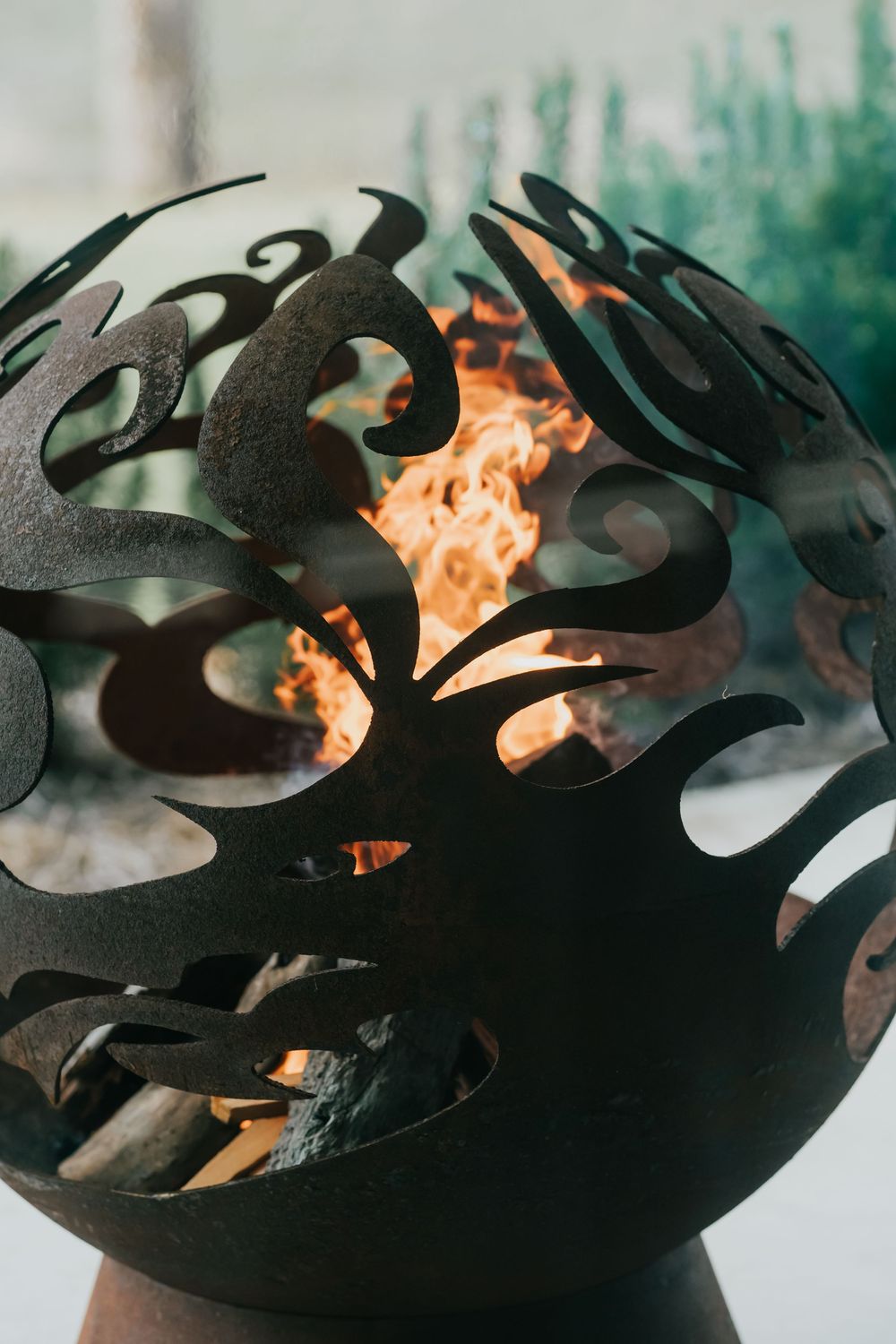 A series of black metal decorative pieces with silhouettes of birds in front of orange flames and green foliage.