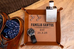 Rustic wooden serving tray with engraved text displaying family name and established date against a textured surface.