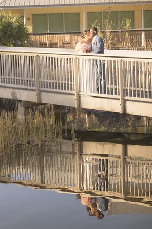 White railing and wooden boardwalk reflect in calm water creating mirror-like symmetry along a waterfront path.