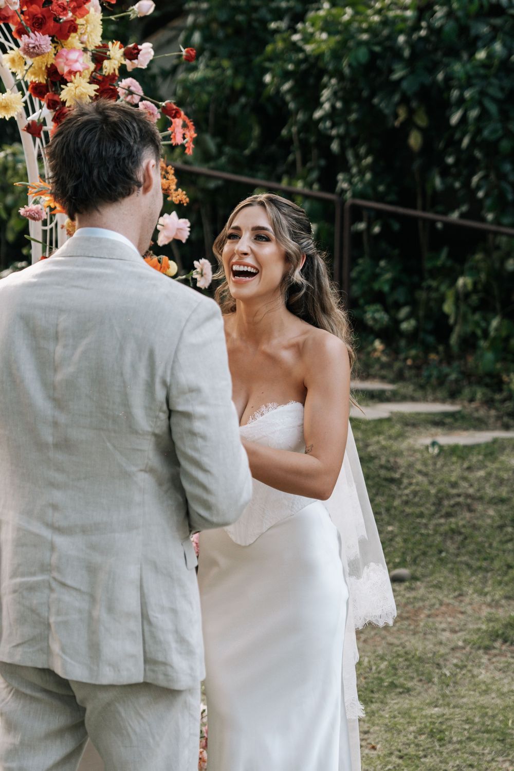 Bride and groom share an intimate moment with colorful florals and balloons in an outdoor garden setting.