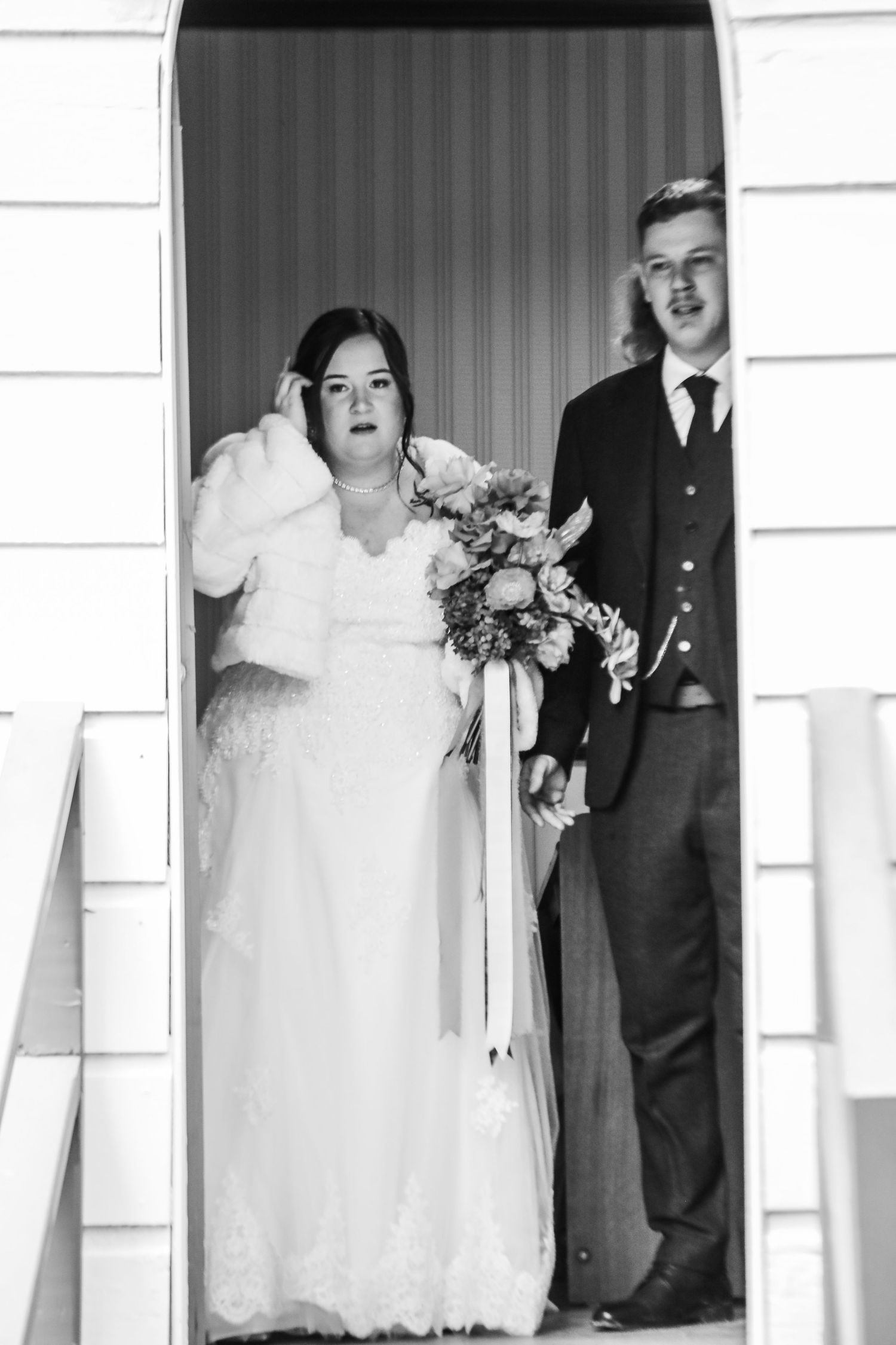 Black and white wedding portraits showing candid moments in front of white architecture.