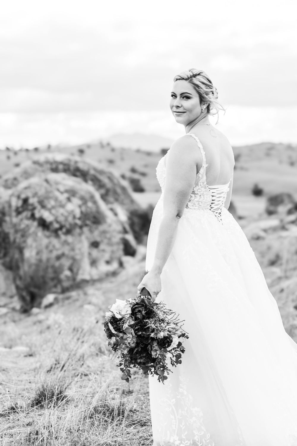 An elegant white wedding dress with lace details captured against rolling hills.