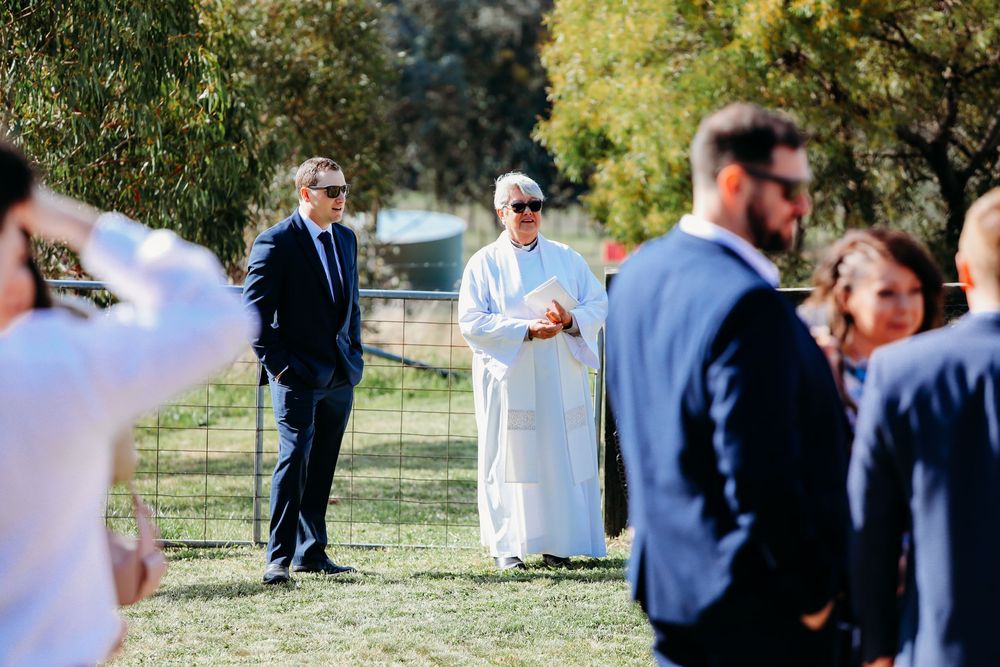 Wedding ceremony guests gathered outdoors with mountains and greenery in the background.