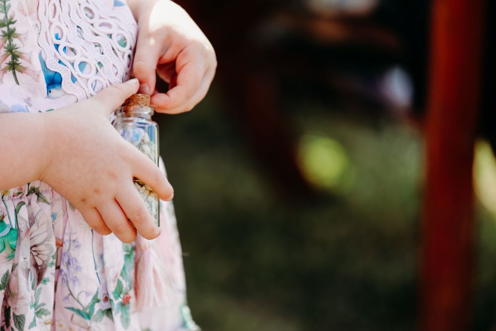 Close-up of small hands fidgeting with a colorful floral patterned dress in natural outdoor lighting.