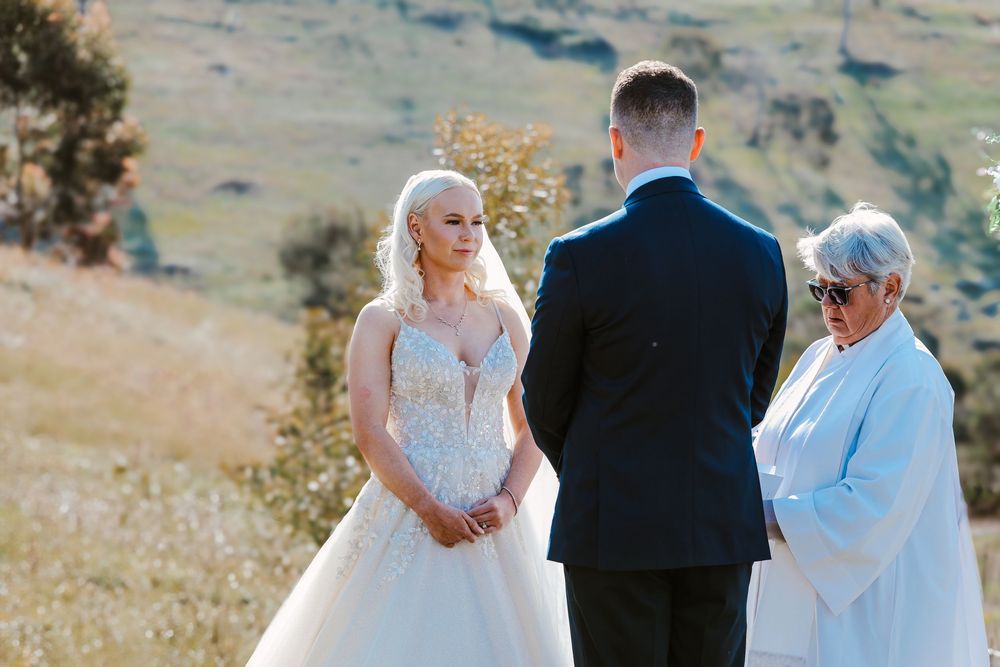 A scenic outdoor wedding ceremony with rolling hills and natural landscapes in the background.