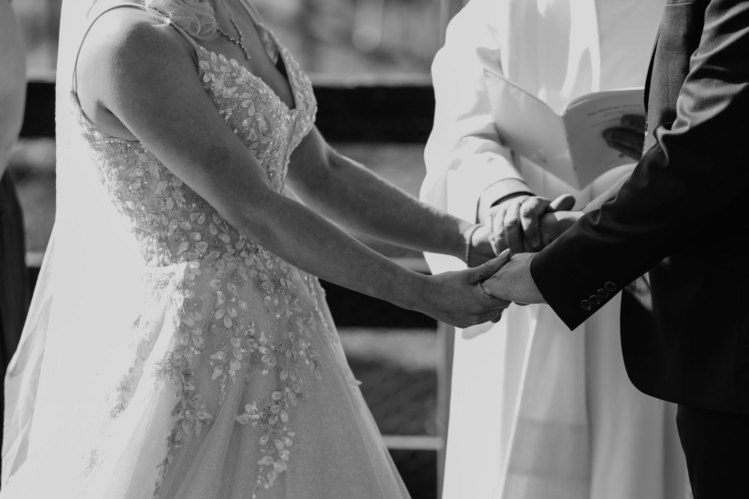 Wedding ceremony moment captured in black and white showing clasped hands.