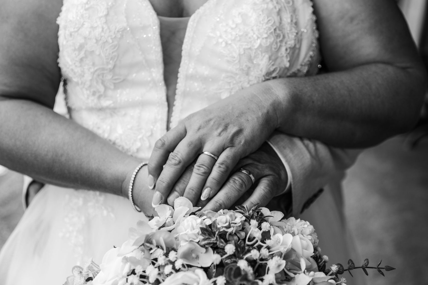 Close-up of wedding bouquet and dress details in black and white.