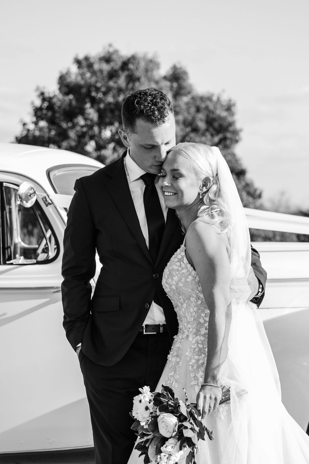 Classic black and white wedding photos in front of a vintage car.