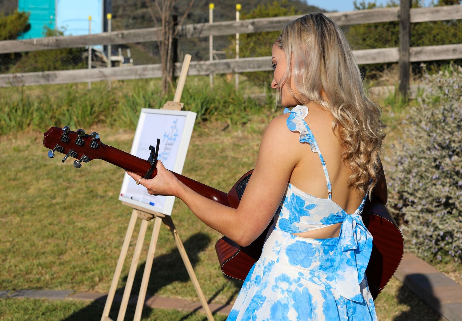 Wedding guests in blue dresses holding musical instruments outdoors.
