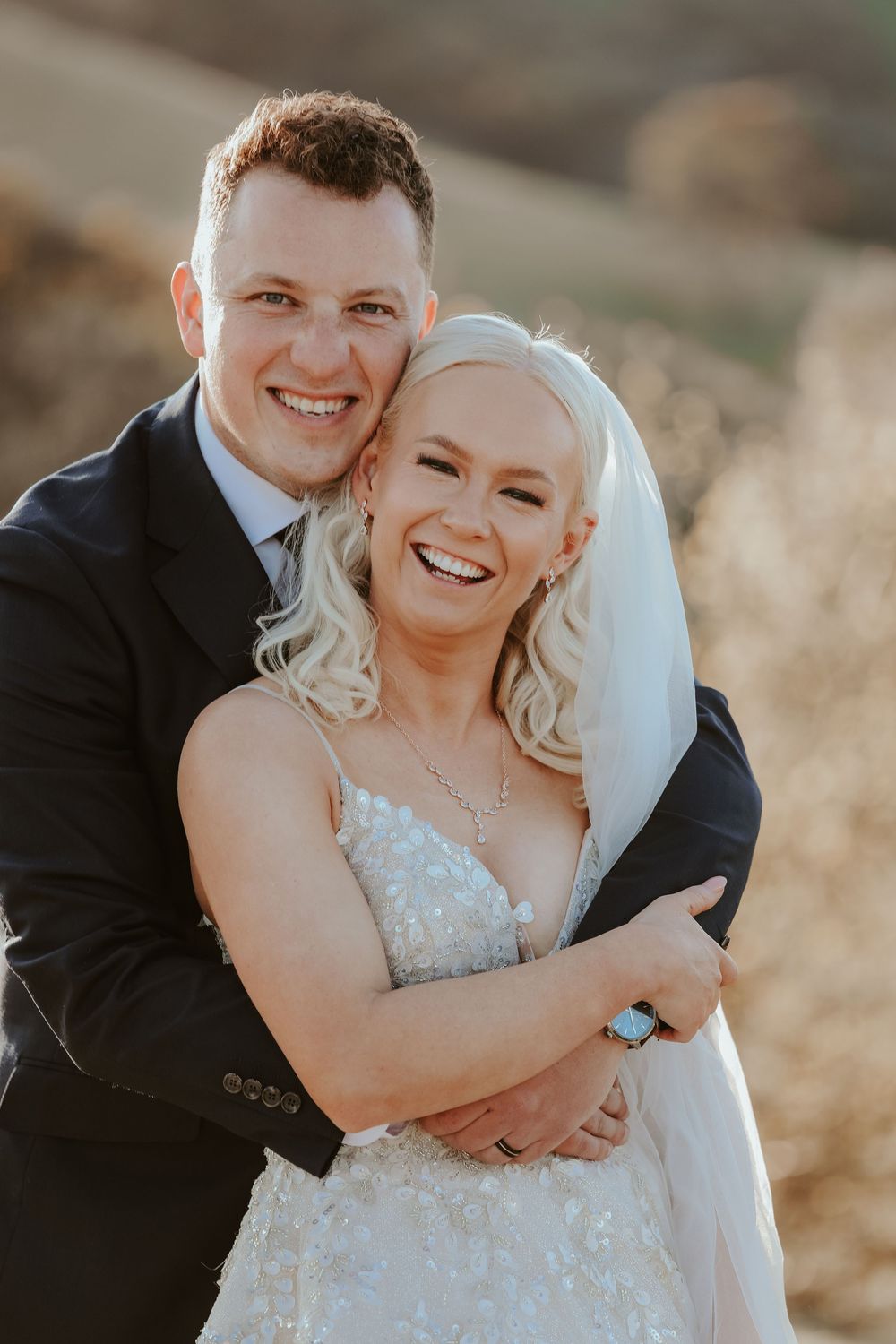 Romantic wedding portrait against mountain backdrop during golden hour.