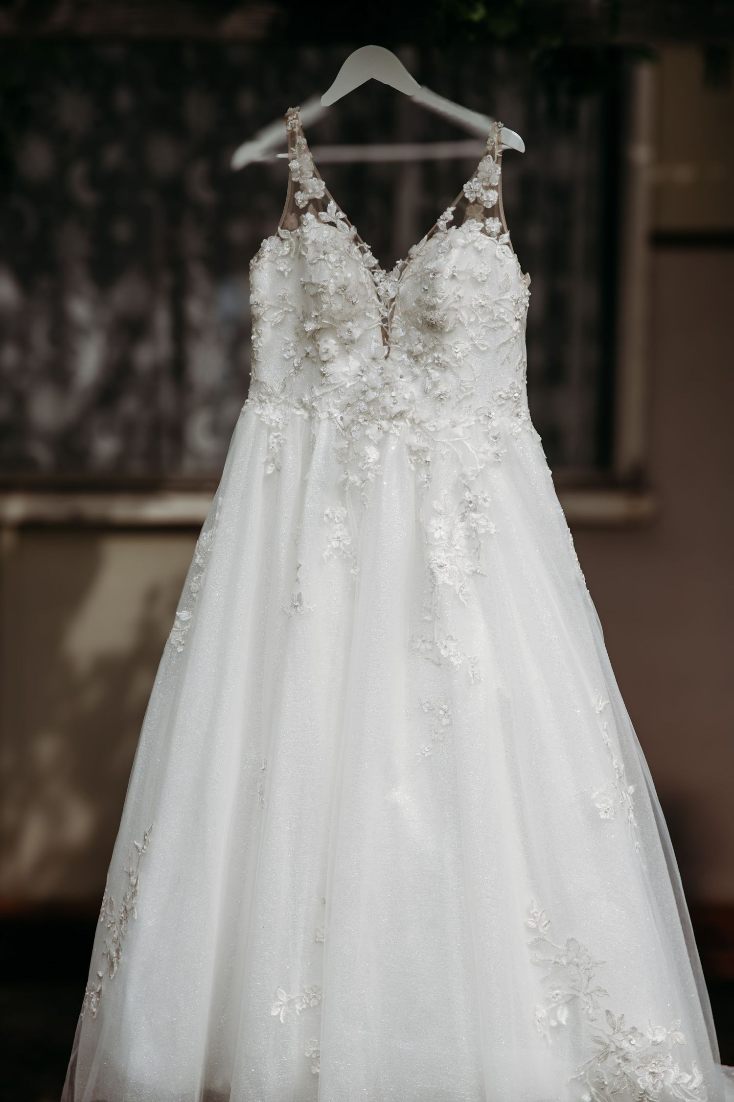 Elegant white wedding dress with lace details hanging on display.