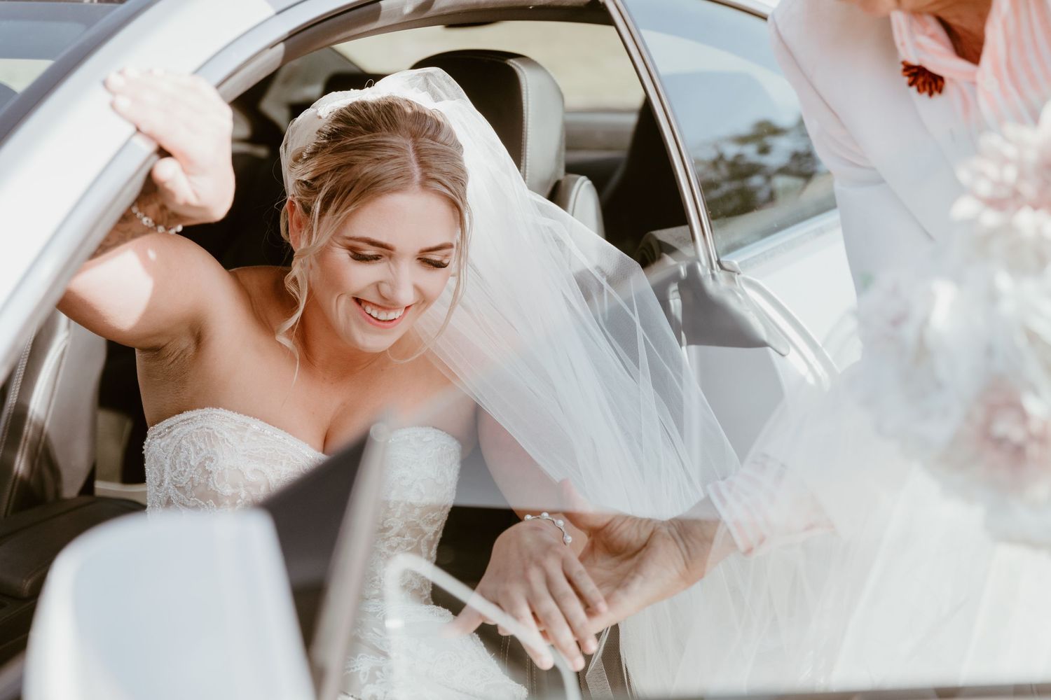 Candid moment of laughter and joy captured between newlyweds in a car.