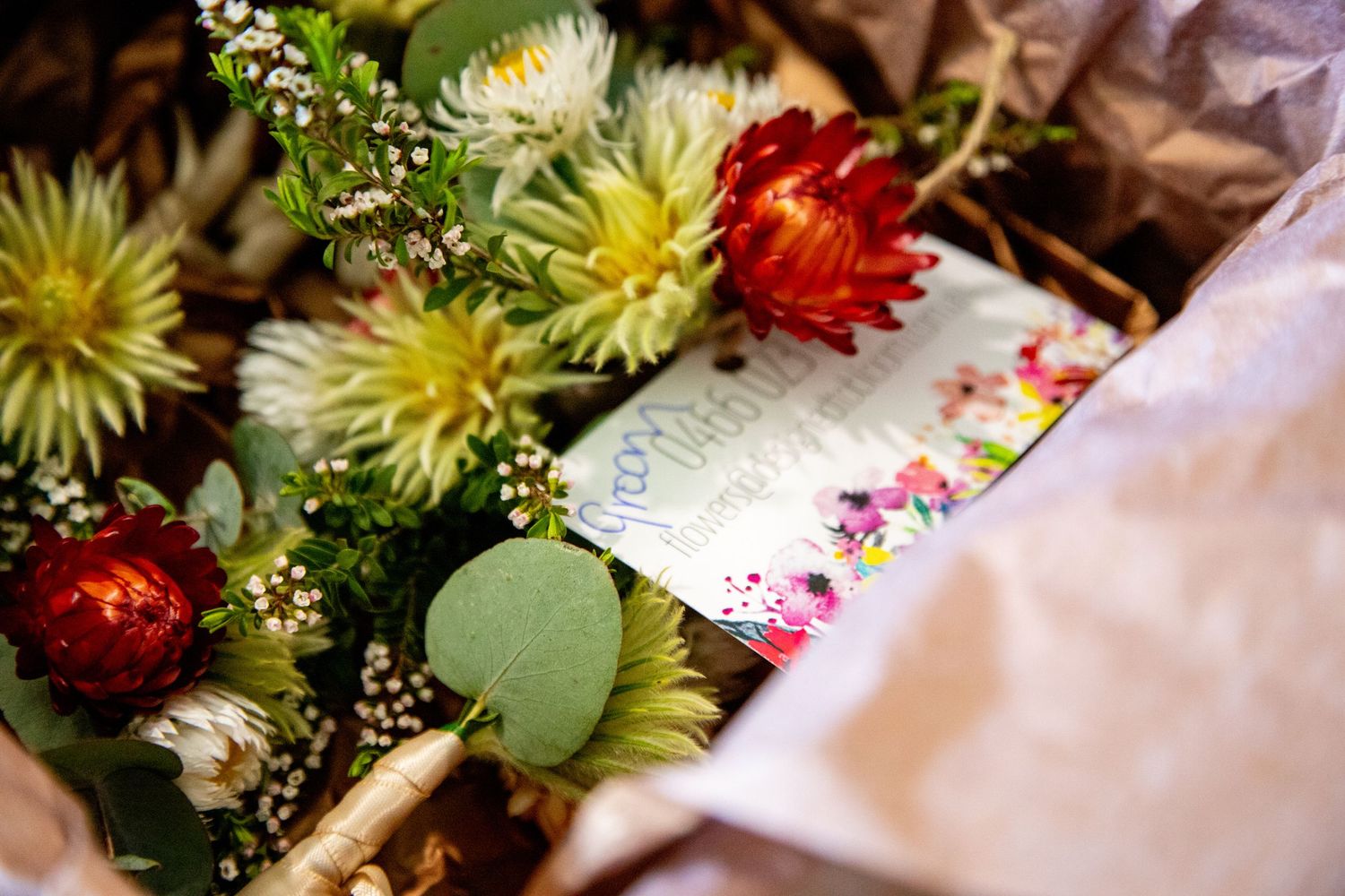 Colorful floral arrangement with dahlias, chrysanthemums and greenery in rustic setting.