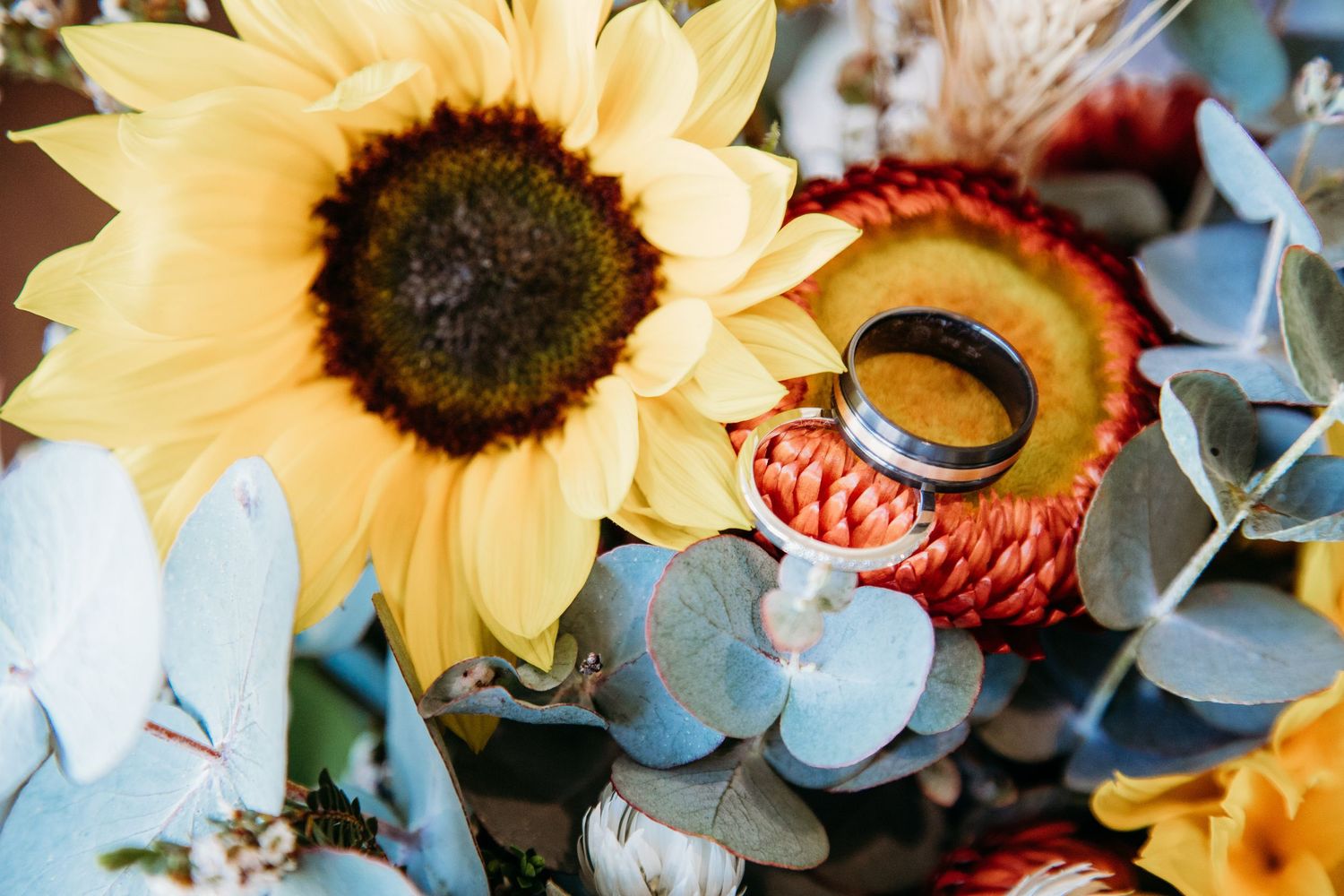A close-up photo of vibrant yellow sunflowers mixed with other floral elements in soft lighting.
