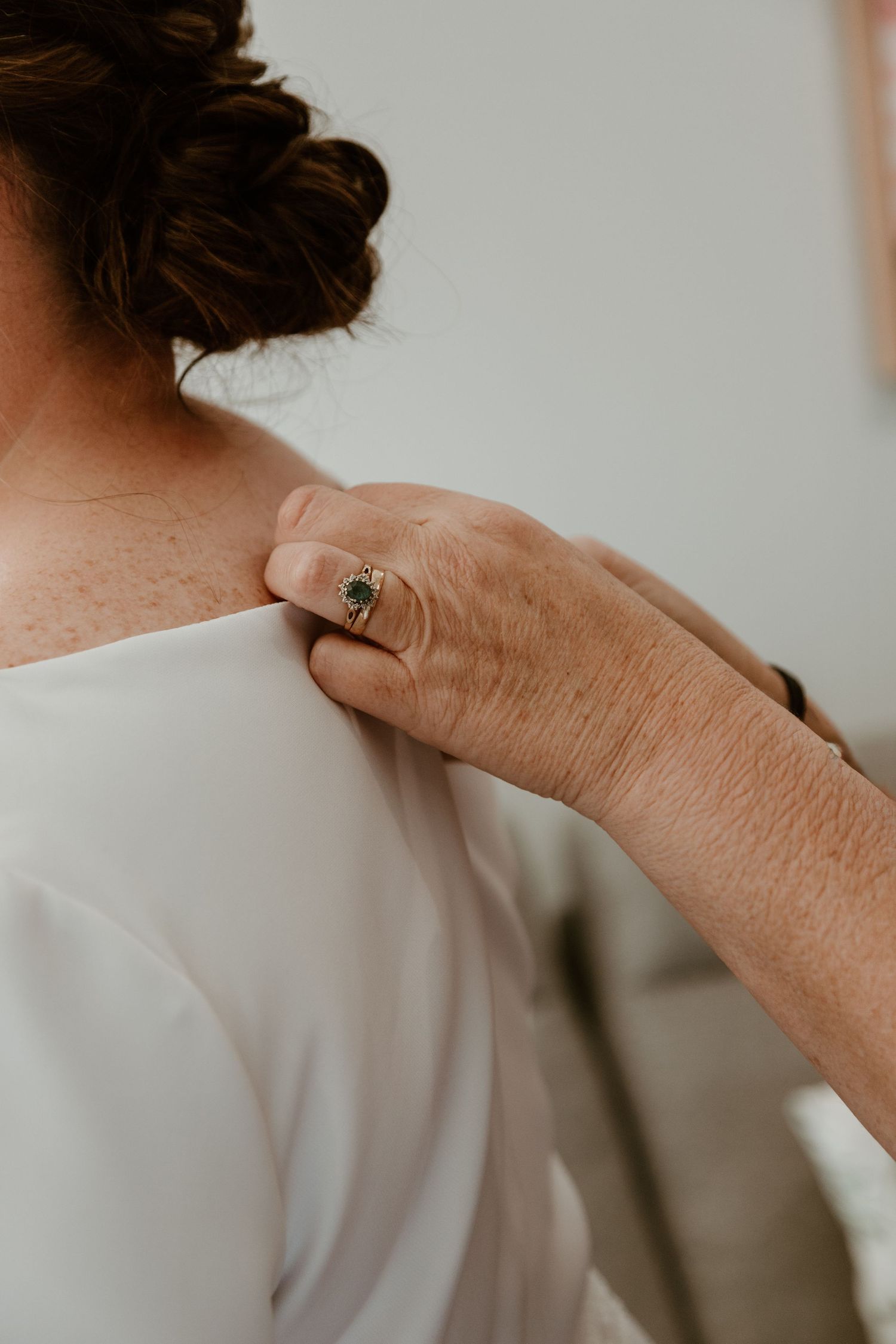 A tender moment captured showing hands gently touching a neck in soft, natural light.