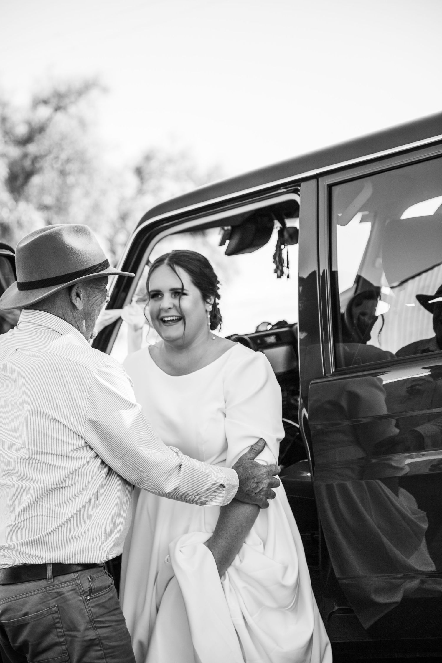 A sequence of black and white photographs showing a sweet moment exchanging affectionate hugs near a car.