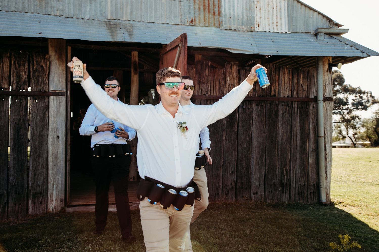 Dancing and celebrating outdoors near rustic barn structure at sunset.