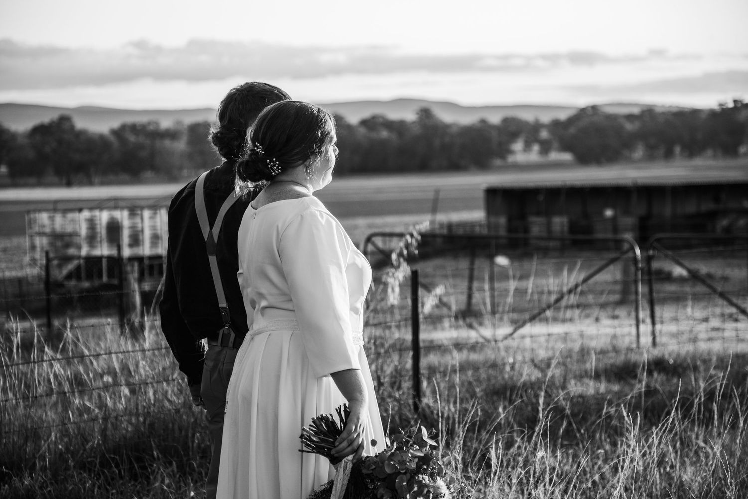 Romantic silhouettes of a couple embracing in a rustic outdoor setting at sunset.