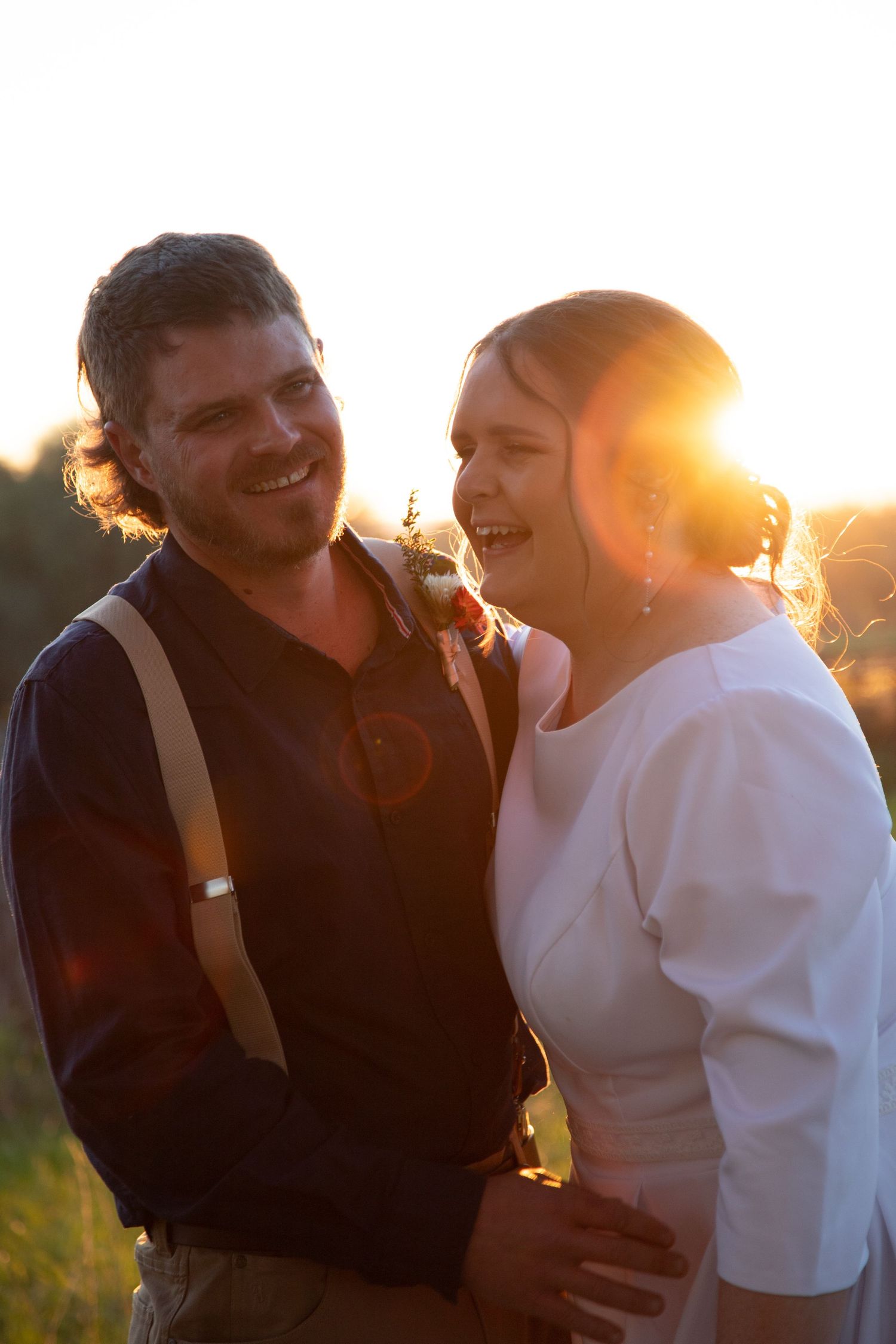 A romantic sunset photoshoot shows a couple embracing in soft golden light.