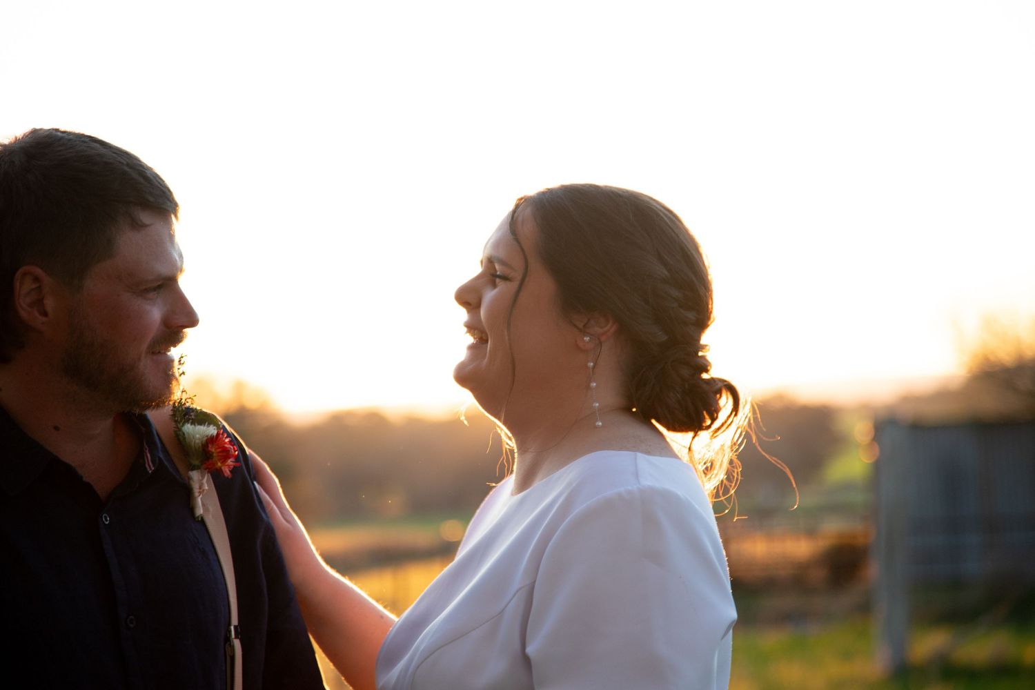 Silhouetted couple sharing a romantic moment in a golden meadow at sunset.