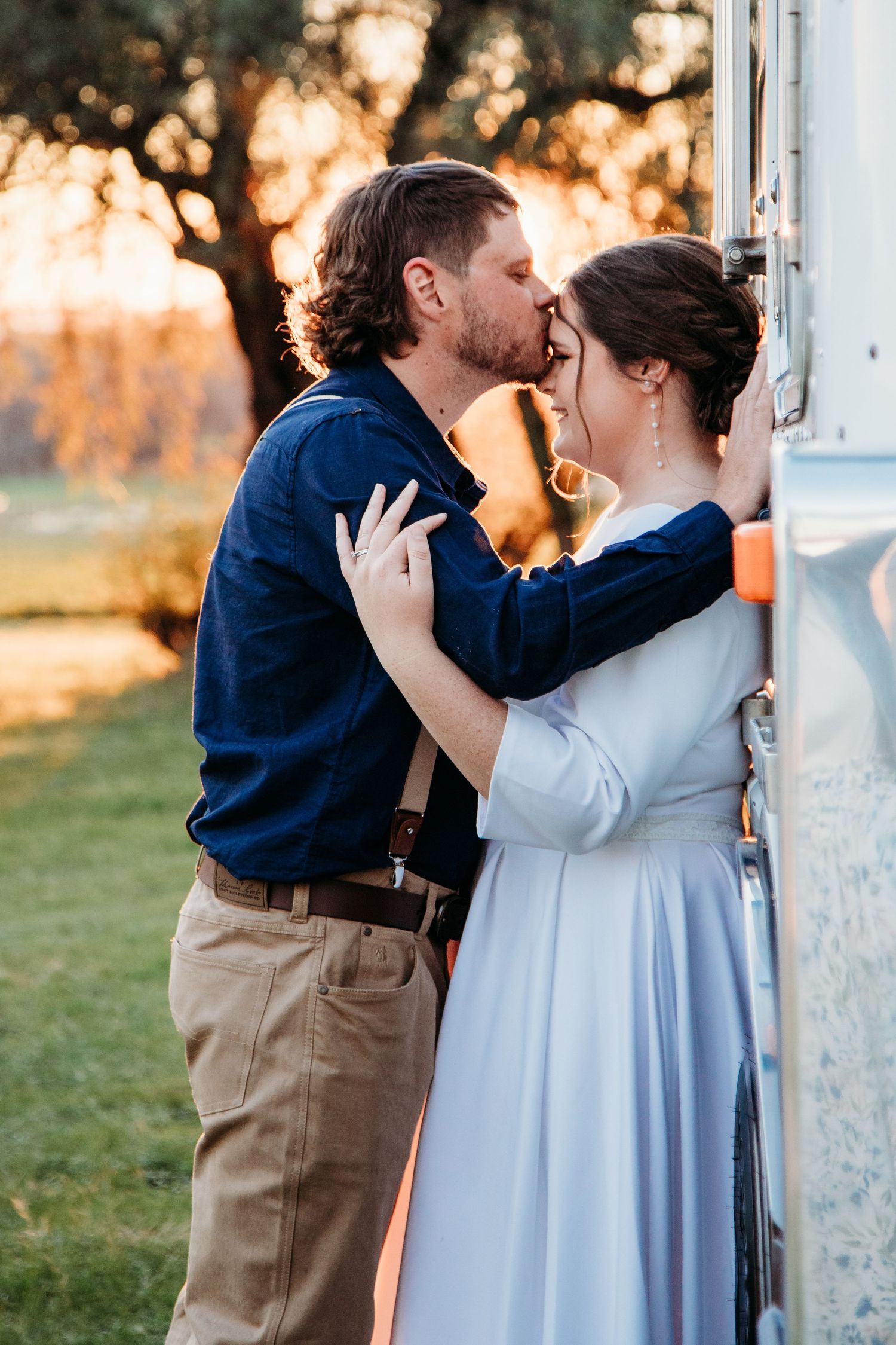 Romantic sunset wedding photos show couple embracing against white pillars in golden light.